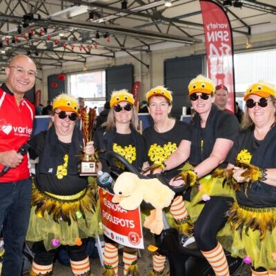 Variety Spin4Kids CEO Mohammad Aldergham hands trophy to best dressed team dressed in brightly coloured yellow and orange bumblebee costumes
