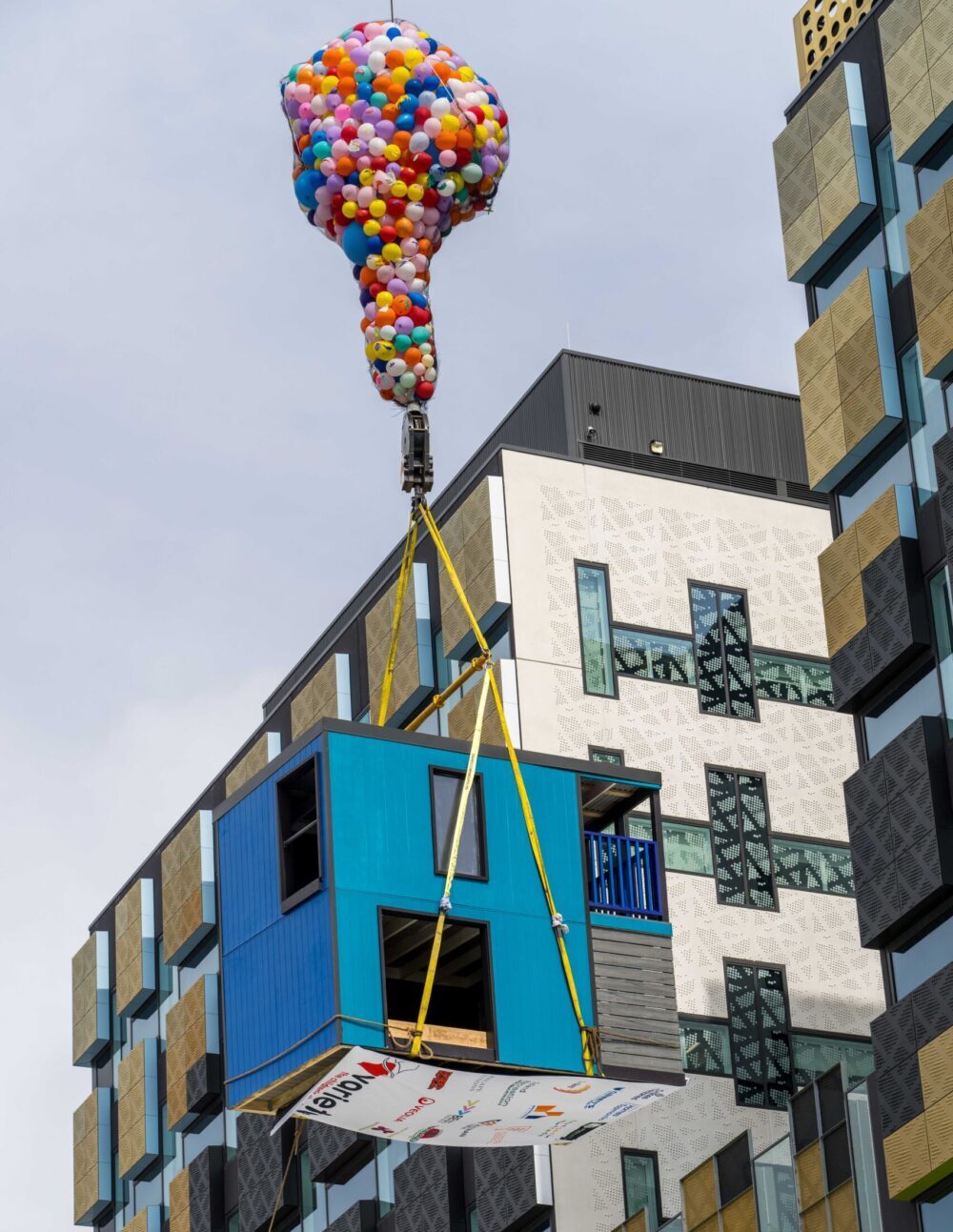 child's cubby house is lifted to the roof of the Royal Hobart Hospital aided by a hundred helium balloons